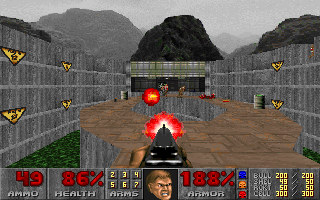 A first-person shooter view displays a demonic red skull-faced enemy in the center of a brown stone floor arena. Concrete brick walls with yellow warning stripes line both sides, receding into a misty gray background. Seven yellow skull decorations float above the arena space. The bottom UI shows a health bar at left reading 100, armor at 100, ammunition counts in the center columns, and a portrait of the player character in the lower-left corner. The pixel art uses a limited color palette typical of early 1990s DOS graphics.