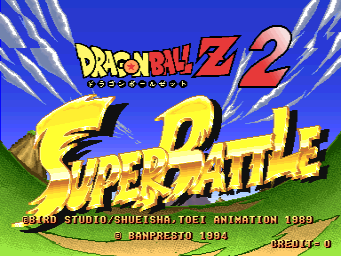 The arcade title screen displays 'Dragon Ball Z 2' in large yellow letters at the top with Japanese characters below, followed by 'Super Battle' in pink text centered on the screen. A bright blue background fills the upper half with white radiating lines emanating from the center. Green grass terrain spans the lower portion. Credits appear at the bottom: 'Banpresto Studio/Shueisha/Toei Animation 1989' and '© Banpresto 1994', with 'USED AT 0' visible in the lower right corner. The art style uses bright colors typical of 1990s arcade sprite-based graphics with a pixelated aesthetic.