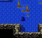 A sprite-based aerial view shows a player character standing on rocky brown terrain against a bright blue pixelated sky background. Three golden castle or tower structures appear in the upper portion of the screen. The low-resolution sprite work and color palette are typical of Game Boy graphics from the 8-bit era.