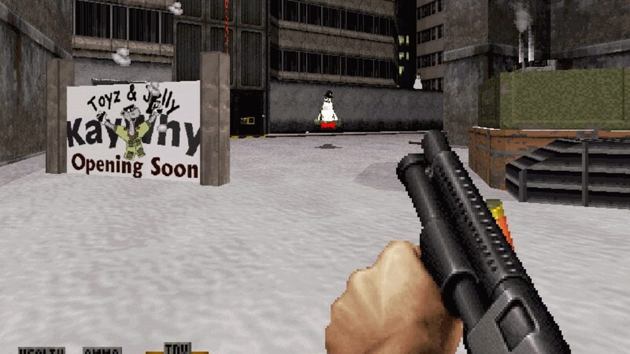 A first-person shooter view holds a shotgun with a tan grip in the lower right. The industrial urban courtyard features concrete buildings with barred windows, a yellow industrial crane, and scattered metal debris on the ground. A white banner reading "TOYZ & JELLY Kaytrinhy Opening Soon" leans against a pillar on the left. A penguin character in red stands on a platform in the center distance. The HUD displays health and ammo counters at the bottom. Pixelated 3D geometry and a muted gray-brown color palette characterize the early-to-mid 1990s game engine aesthetic.