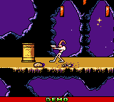 Earthworm Jim stands on a yellow platform against a purple background with dark architectural structures. The character is rendered in colorful pixel art with a red health bar displayed at the bottom of the screen. Purple jagged shapes frame the level, creating a narrow passage environment. The Game Boy's characteristic low-resolution sprite work and limited color palette are visible throughout the scene.