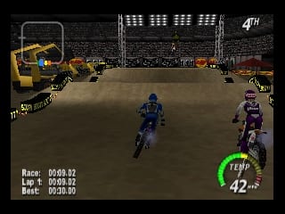 A motocross race in progress on a dirt track with two riders visible in the center of the frame—one in blue on the left and one in purple on the right. Industrial buildings and spectator structures form the background. A heads-up display in the lower left shows race information including lap count and best time. A green speedometer displaying 42 mph appears in the lower right corner. The scene uses a brown and tan color palette for the terrain with darker architectural elements framing the arena.