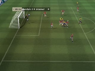 A soccer match is in progress on a green pitch with white field markings. The camera is positioned behind one goal, showing the white goalkeeper in the net on the left side. Red and white player models are scattered across the field in typical match formation. A HUD bar at the top displays team names and score information. The graphics use low polygon counts and flat shading typical of N64-era sports games, with a simple green grass texture and pixelated player sprites.