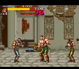 A side-scrolling beat-em-up scene displays three muscular characters in fighting stances on a tiled floor with ornate wall panels and decorative urns behind them. The HUD shows a score of 1700 in the upper left, a life meter at top center, and time remaining at top right. The character sprites are rendered in bright colors with defined musculature, set against a beige stone interior with detailed background architecture in a 16-bit SNES visual style.