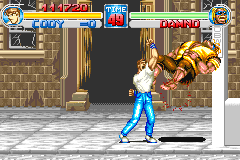 A player character in blue jeans and white shirt stands in the center of a stone-walled street environment, facing a large brown enemy with a tiger-striped pattern on the right side. The HUD displays health bars at the top, score information in the upper corners, and a stage indicator. The sprite-based graphics show typical GBA resolution with a beige and gray color palette for the architectural background. Another character model is visible on the left side of the screen.