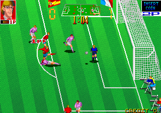 A soccer field viewed from above shows five player sprites in magenta and blue uniforms positioned across the green pitch. White field markings include the center line, goal area, and penalty box. A goal net appears on the right side. The top-left corner displays a red UI panel with game information, while a blue scoreboard appears in the upper-right corner. The sprite style is low-resolution with distinct pixelation typical of early 1990s arcade graphics.