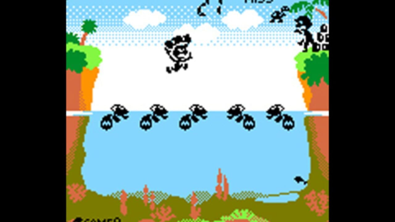 A side-scrolling level displays a blue water body with five black ant-like creatures walking across a sandy shore at water's edge. Above the water, a single creature jumps in mid-air against a bright sky with white clouds and green trees lining both cliffs. Red coral-like plants dot the sandy ground below. The color palette uses bright greens, blues, oranges, and blacks with a dotted background pattern typical of Game Boy Color graphics.