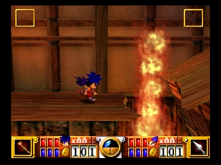 A blue-haired character in colorful attire stands on a wooden floor facing a large wall of flames in the center-right of the screen. Two small brown enemies are visible on the wooden platform. The background shows interior architecture with windows and warm orange-brown tones. At the bottom, a HUD displays a score panel with yellow and red segments flanking a circular health or power indicator in the center. Small yellow square icons appear in the top corners of the screen.