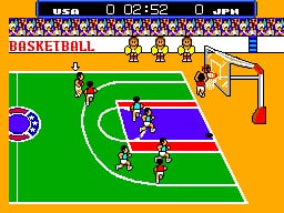 A basketball court viewed from an overhead angle occupies the center of the screen, rendered in green with purple and blue rectangular areas marking key zones. Two pixelated player sprites in orange and blue jerseys are positioned on the court, with the ball visible near the basket. The top of the screen displays a yellow header bar containing game information including time (02:52), score (USA 0, JPM), and the word "BASKETBALL" in white text. The surrounding area outside the court is bright orange, and the left side shows a partial score indicator with a circular icon. Low-resolution 8-bit sprite graphics and a flat color palette are characteristic of early SMS sports games.