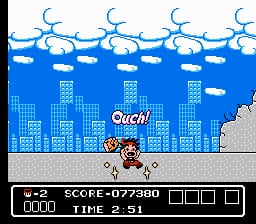 A pixelated side-scrolling scene shows a small character in the foreground standing on gray ground before a blue cityscape with tall buildings. White clouds and blue crescent moons fill the sky at the top. The word "Ouch!" appears in white text near the center. A black status bar at the bottom displays "LIFE 2", "SCORE: 079960", and "TIME 2:51" with empty checkbox squares to the right.
