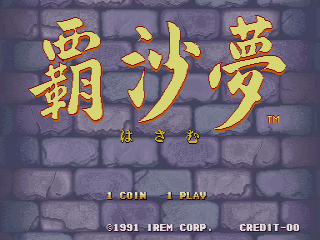 The title screen displays large yellow Japanese characters centered on a gray brick wall background. Below the title are smaller characters and a trademark symbol. At the bottom, white text reads '1 COIN' and '1 PLAY' on the left, with '©1991 IREM CORP.' and 'CREDIT-00' aligned to the right. The overall color palette uses muted grays, yellows, and blacks typical of early 1990s arcade graphics.