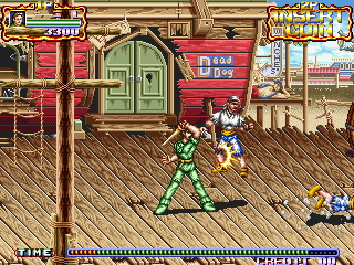 A player character in green and red sprite armor stands center-stage on a wooden dock platform, facing two blue enemies to the right. A red building with a green door occupies the left side, while colorful carnival or harbor structures line the background under a tan sky. The HUD displays a red health bar at top-left, score information at top-right, and a yellow and blue status bar spanning the bottom of the screen. The pixel art uses a warm color palette typical of early 1990s arcade hardware.