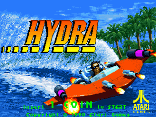 The Hydra title screen displays the orange game logo in large letters across the upper center, with a jet ski rider on an orange watercraft riding a large blue wave in the background. Tropical palm trees line the right side against a blue sky with white clouds. At the bottom, yellow text reads "PUSH START TO BEGIN" with "ATARI GAMES" visible in the lower right corner. The scene uses bright blues, oranges, and greens typical of early 1990s arcade graphics.