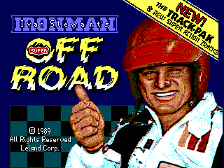 The title screen features a pixelated portrait of a man wearing a red baseball cap and white racing suit with a red stripe, smiling and giving a thumbs-up gesture in the center-right area. Blue text reading "IRONMAN" appears in the upper left, with "OFF ROAD" in large yellow letters below it. A yellow banner in the upper right corner contains "NEW" and "REALISTIC" text. The "Leland Corp" copyright notice and "© 1989" date are displayed in the lower left corner against a dark blue background with a checkered pattern strip running horizontally across the middle section.