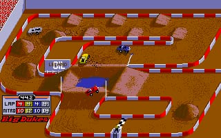 An overhead view of a dirt off-road racing circuit rendered in brown tones with tan and gray rock formations scattered across the landscape. Two vehicles with different colored bodies navigate a winding track marked by red and white checkered barriers. The left side displays a HUD panel with race statistics, lap counter, and speed information in blue and white text. Pixelated sprite-based graphics show the angular art style typical of early 1990s DOS racing games, with the track presenting a challenging maze-like course layout.