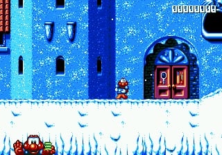 A small red and yellow cat character stands on a snow-covered ground in the center-left of the frame, facing a large blue castle wall with two red doors and multiple small square windows. The background shows a bright blue starry sky with white falling snow, creating a winter scene. Icicles hang from the snowy ledge where the character stands, and a score counter displays in the upper right corner. The sprite-based graphics use a limited color palette typical of 16-bit Sega Genesis era gaming.