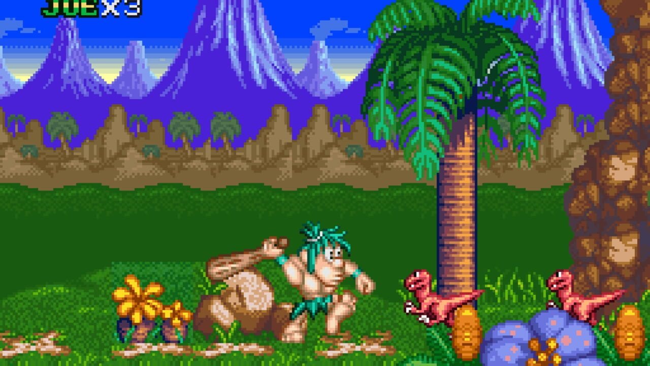 A caveman character with brown skin and blue hair stands in the center of a green grass field, wielding a club. Two red dinosaurs with yellow spots move across the ground on either side. A large tropical tree with green foliage and orange trunk dominates the right side. Purple mountains with striped textures fill the background against a blue sky. Small yellow flowers and blue eggs with orange spots scatter across the foreground. A brown rock formation with faces appears on the far right edge. The "JQESX3" score display appears in green text at the top left corner.