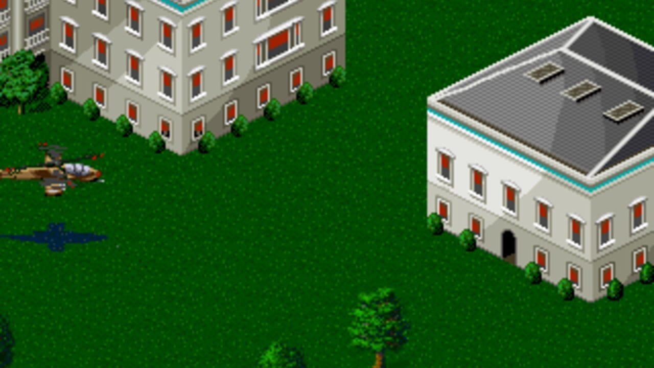 An isometric-view level displays two large concrete buildings with red-outlined windows and turquoise trim set on bright green grass. The left structure is a tall corner building, while the right is a single-story structure with a dark roof. Small green bushes and trees dot the landscape. A helicopter sprite appears in the upper left area, and blue text or UI elements are visible in the lower left corner. The 16-bit sprite art uses a limited color palette typical of early 1990s console graphics.