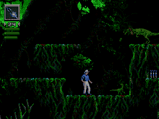 A blue-suited human character stands centered on a narrow green platform surrounded by tall green vegetation walls against a black background. The character is depicted as a small sprite in a side-scrolling environment. A HUD element appears in the upper left corner showing game status. The scene uses a limited color palette of green, black, and blue with low-resolution 16-bit sprite graphics typical of early 1990s Sega Genesis games.