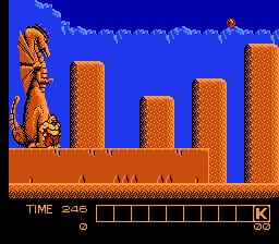 A character stands on the left side of a brown platform against a bright blue background, with five tall orange brick columns of varying heights arranged across the platform. The character appears to be a muscular figure with orange/red coloring and a curved posture. A row of white clouds is visible in the upper portion of the sky. At the bottom of the screen, a white text display shows "TIME 240" on the left and a series of small rectangular boxes forming a progress or weapon bar, with a "K" indicator on the right. The sprite work uses the characteristic low-resolution pixelated style of 8-bit NES games.
