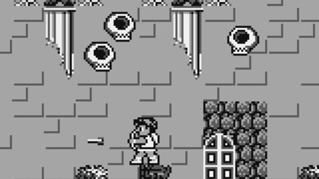 A pixelated monochrome Game Boy gameplay scene shows a small humanoid character standing on a stone platform in the center of a gray brick maze. Two floating round enemies with black pupils hover in the upper portion of the screen, one slightly left of center and one on the right side. Vertical chains or curtains hang from two pillars at the top corners. A textured brick wall structure occupies the right side of the screen, and various stone platforms form the level's architecture throughout. The sprite art uses limited detail with black outlines against the gray background.