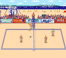 A beach volleyball court divides the screen horizontally, with two players in tan-colored sprite form positioned on opposite sides of the net. The sand court is bordered by white lines. Above the court, a crowd of spectators fills stadium bleachers rendered in small pixel sprites, with blue sky and structural beams visible at the top. Sponsor logos and advertising boards line the background behind the crowd, displayed in red and blue banners. A scoreboard or status information appears at the bottom left of the screen in a blue UI panel.