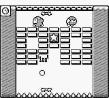 A Game Boy gameplay screen displays Kirby's Block Ball with a vertical playing field centered on the display. The game board shows multiple rows of colored blocks arranged in a grid pattern, with Kirby's sprite visible at the top center. Two paddle-like elements appear to be positioned at the sides of the field. The bottom portion shows a status area with score information and remaining balls indicator. The screen uses the monochromatic green-tinted palette typical of original Game Boy hardware, with black sprites and block elements against the lighter background. A dotted border frames the entire play area.