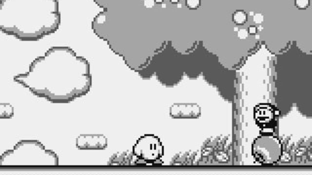 A white round character with a simple face stands in a grassy field with a stone pillar on the right side. Dark jagged mountain terrain forms the background, with a gray sky above. White rounded cloud shapes float on the left, and small horizontal platforms are scattered throughout the middle ground. A black-and-white sprite character appears in the upper right corner. The monochrome palette and pixelated art style are typical of Game Boy hardware, with visible sprite-based animation and simple terrain tiles composing the landscape.