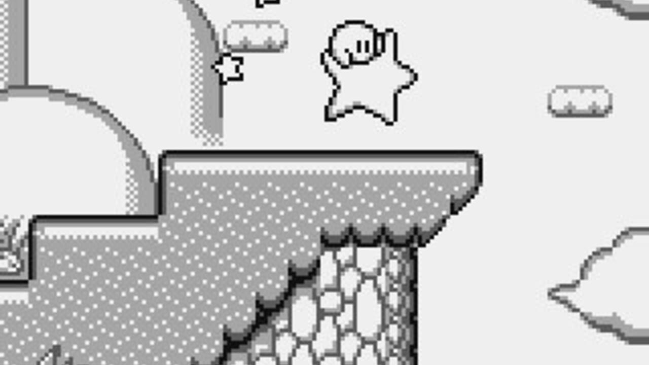 Kirby, a white rounded character with a small mouth, appears in the upper center of a monochromatic gray and white level. Below him stretches a textured platform with a dotted pattern, featuring brick-like structural elements descending into the lower portion. The stage shows tile-based architecture with dark outlines and varying shades of gray. A small icon or UI element appears in the upper right corner. The pixel art uses a limited grayscale palette typical of Game Boy graphics, with solid black borders defining the level geometry and character sprite.