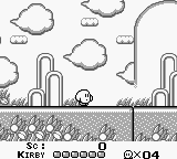 A Game Boy screenshot displays Kirby as a small pink sprite in the center-right of a side-scrolling level. The stage features cactus-shaped obstacles and clouds in the background, with a ground terrain at the bottom showing scattered debris or rocks. The HUD shows Kirby's health as five filled circles, the word "KIRBY" on the left, and "2×04" in the bottom-right corner, likely indicating level progression. The entire scene is rendered in monochrome with black lines and outlines typical of early Game Boy graphics.