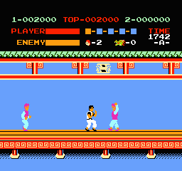 A blue platform spans the middle of the screen with three sprite characters standing on it—one in pink on the left, one in yellow in the center, and one in white on the right. The top third displays a heads-up display with red and yellow text showing score (1-002000), level indicators, player status bars, and enemy count (6-2, with 0 remaining). An ornamental brown and orange patterned border frames the bottom portion of the play area. The background uses a solid blue color typical of 8-bit NES graphics.