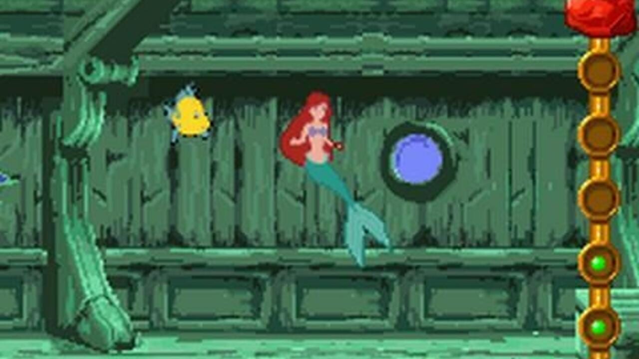 A red-haired mermaid character with a teal tail stands in the center of an underwater cavern with green stone walls and vertical seaweed textures. A yellow fish swims to the left, and a blue circular object floats to the right. The right edge displays a vertical golden instrument panel with three brown circular buttons and two green circular indicators at the bottom. A red object with a yellow base appears in the upper right corner. The scene uses 16-bit sprite graphics with a limited color palette of greens, blues, and earth tones typical of Game Boy Advance hardware.