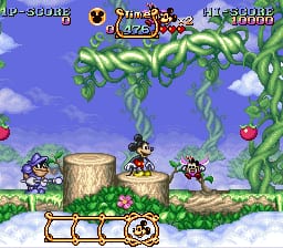 Mickey Mouse stands in a colorful forest level with green vine platforms suspended above ground. The scene features wooden logs and a grassy landscape with blue sky and white clouds in the background. At the top, a score display reads "10-50006" with "Charge" at 4/4 and "Life 30009" visible. Four pixelated enemies appear scattered across the platforms. The UI shows Mickey's current power state and life counter at the bottom in a beige panel. The sprite work displays SNES-era 16-bit resolution with vibrant greens and blues.