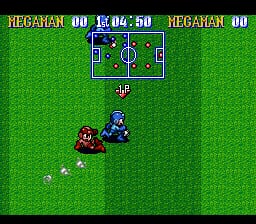 A soccer field occupies the center of the screen with a small overhead view showing player positions and a ball. Two sprite characters—one red and one blue—face each other on the grass pitch. The score display at the top reads 'MEGAMAN 00' on both sides with '15:04:50' in the center. The green grass fills the entire background with a bright, flat color palette typical of SNES-era sports games. White dotted lines mark the ball's movement trail on the field.