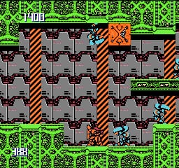 A small blue robot stands in the center of a gray tile-based maze with red and white striped vertical walls dividing the corridors. Orange explosion effects appear in the upper-right area. The background displays a bright green repeating pattern with interlocking geometric shapes. The playfield is surrounded by a thick green border frame containing the game's HUD elements. The overall visual style uses limited sprite resolution and a bright 8-bit color palette typical of early NES games.