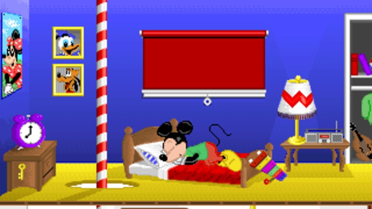 Mickey Mouse lies in a bed with red blankets in a bedroom scene with a bright blue wall and yellow floor. A red and white striped pole stands behind the bed. On the left, a purple alarm clock sits on a brown wooden chest with a yellow key icon. Two framed portraits of Donald Duck and another character hang above in yellow frames. The right side shows a small wooden table with a red and white lamp with a yellow top, and a shelf unit with colorful objects. A toy train with rainbow-colored cars sits on the yellow floor. The top of the screen displays a red rectangular window or banner. The overall aesthetic features low-resolution pixel art typical of early 1990s DOS games.