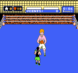 A boxer with blonde hair and red boxing gloves stands in the center of a blue boxing ring, viewed from behind. The opponent, a smaller figure in yellow shorts, is positioned directly across in a fighting stance. The top of the screen displays a scoreboard with white text showing round number, points, and health indicators on a red and blue background. The ring floor is rendered in brown and tan pixels with a decorative rope border visible at the top edge. The entire scene uses NES-era sprite graphics with distinct pixelation typical of 8-bit fighting game visuals.
