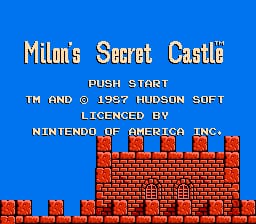 The title screen displays "Milon's Secret Castle" in large white text at the top against a bright blue background. Below are white text lines reading "PUSH START," "™ AND © 1987 HUDSON SOFT," "LICENCED BY NINTENDO OF AMERICA INC." The lower half shows a red brick castle structure made of pixelated blocks in a 8-bit style, with crenellated walls and a recessed center section, rendered in shades of red and orange.