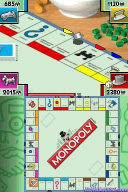The Monopoly DS board game interface displays the iconic red MONOPOLY logo centered on the game board in the lower half. Above, a wooden table holds a physical Monopoly board setup with property cards, dice, and tokens visible in the background. The top of the screen shows four corner panels with distance markers (685m, 1130m, 2015w, 2380m) in yellow boxes. The bottom screen features the digital game board with colored properties arranged around the edges, property cards visible in a grid layout, and purple and white UI elements framing the board. The graphics use flat, simplified 2D sprites typical of Nintendo DS era games.