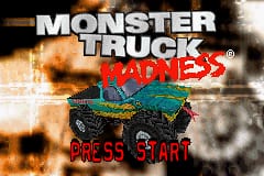 The title screen displays "MONSTER TRUCK" in large white capital letters at the top, with "MADNESS" in red below it. A green monster truck with oversized tires is centered in the middle of the screen, positioned against an orange and brown explosion effect with smoke clouds in the background. At the bottom, "PRESS START" appears in red text. The overall color palette consists of warm tones—oranges, browns, and yellows—contrasting with the green vehicle and white title text.