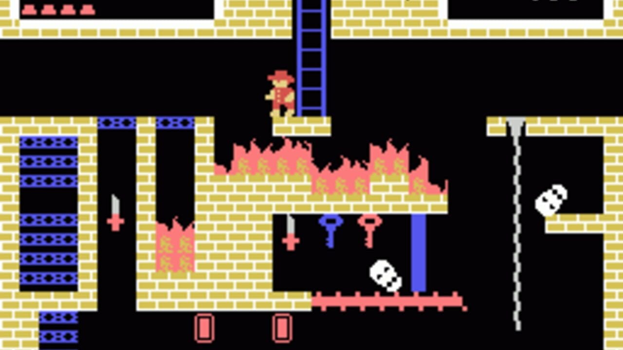 A small red and yellow pixelated character stands on a blue ladder near the top center of a multi-level brick structure. Below, pink and yellow flames occupy the middle section, with white skull sprites and blue and red cross or key symbols scattered across black platforms. On the left side, a tall vertical shaft contains blue patterned blocks. Two pink rectangular objects appear at the bottom of the screen. The scene uses a black background with tan brick patterns throughout, typical of early 1980s arcade-style pixel graphics.