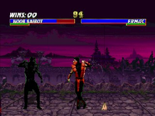 Two fighters stand facing each other on a purple-tinted rocky terrain with mountains in the background. The character on the left wears dark clothing while the figure on the right is dressed in orange and red. Health bars appear at the top of the screen displaying both fighters' remaining health, with player names and round information in white text. The ground is decorated with pixelated rock formations and debris scattered across the stage floor. The overall color palette emphasizes purples and dark tones typical of mid-1990s 3D fighting game graphics.
