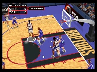 A basketball game in progress on a purple and blue court. Players in dark and light colored jerseys are positioned around the paint and perimeter. The scoreboard at top left shows "IN THE ZONE" with "UTAH" at 8 points and "TOR" at 0 points, marking the 1st Quarter. A white net and backboard are visible on the right side. The camera angle shows an elevated view of the full court layout with the distinctive polygonal graphics style characteristic of Nintendo 64 sports games.