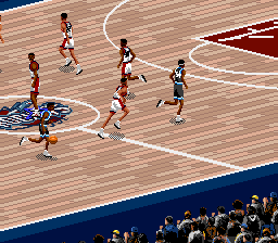A basketball court viewed from above shows five player sprites in motion during a game. Players in red and black jerseys run across the wooden court, with one player dribbling the ball in the lower left. A blue boundary line frames the court edge, and a crowd of spectators sits in the background along the sideline. The sprite-based graphics display the characteristic low resolution and color palette of SNES basketball games.