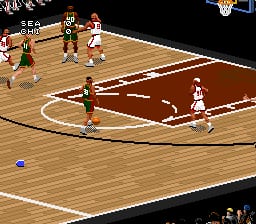 A basketball game in progress displays an overhead court view with two teams of pixelated players in brown and white uniforms positioned across the wooden floor. White lines mark the court boundaries and center circle. A blue ball sits near the bottom of the visible court area. The upper portion shows the opposite end of the court with additional players. The graphics use a flat, isometric perspective typical of 16-bit sports games, with low-resolution sprites and a limited color palette of browns, whites, and skin tones against the tan court floor.