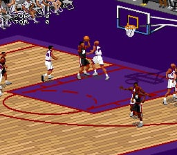 A basketball game is in progress on a blue and wood-textured court. Multiple players in white and dark jerseys are positioned around the court, with one player in a dark uniform dribbling the ball in the lower portion of the frame. A basketball hoop with backboard is visible in the upper right corner. The sprite-based graphics display pixelated player figures typical of SNES-era sports games, with a purple border framing the court boundaries.