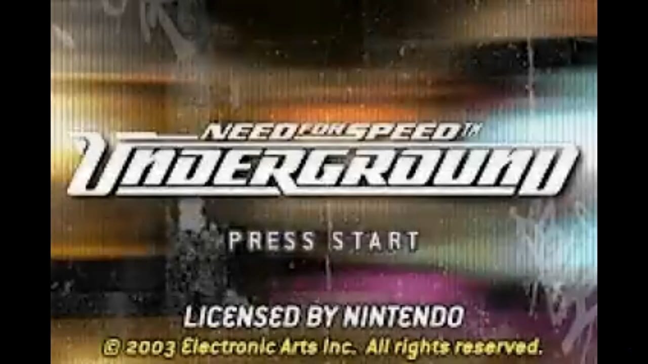 The Need for Speed Underground title logo dominates the center of the screen in bold white italic lettering, overlaid on a blurred background of colorful urban architecture and neon lighting in orange, yellow, and cyan tones. Below the title, "PRESS START" appears in white capital letters. At the bottom, licensing text reads "LICENSED BY NINTENDO" and "©2003 Electronic Arts Inc. All rights reserved" in yellow and white text. The image has a grainy, interlaced appearance typical of early 2000s GameBoy Advance or similar handheld hardware.
