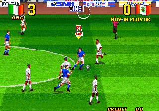 A soccer match in progress on a bright green pitch. Two teams of pixelated players in white and blue jerseys are positioned across the field, with the ball visible in the center area. The scoreboard at top displays "NEOGEO CUP '98" with a 0-0 score. Advertising boards line the stadium perimeter behind the players. The "CREDIT 00" counter appears in the bottom right corner, and a "BUY-IN PLAY OK" message is visible at the top right. The sprite-based graphics show characteristic late-1990s arcade visual style.