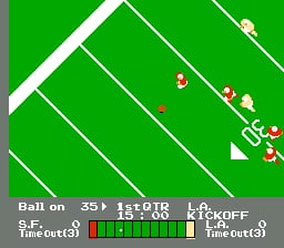A green football field viewed from above displays player sprites in white and red uniforms positioned across the yard lines. The bottom status bar shows offensive formation details, field position markers reading "35" and "1st&OTR", and a horizontal health or stamina meter with green and red segments. White triangular markers and field boundaries define the play area against the bright green grass, with small player icons clustered in the right portion of the screen indicating active gameplay.