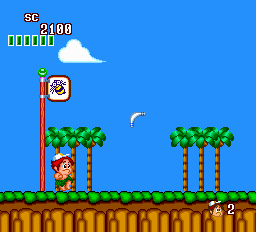 A protagonist in orange stands on a wooden platform in the center-left, facing right beneath a red flag pole. Two palm trees with green fronds flank the scene on either side. The top-left displays a score counter reading 2400 with horizontal progress bars, while the top-right shows a lives indicator with the number 2. A blue sky fills the upper third, a white cloud floats in the distance, and brown tiled ground forms the bottom platform. The sprite-based graphics use a bright, limited color palette typical of 16-bit hardware.